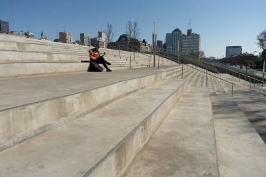 Halka açık bir parkta merdivenlerde gitar çalan şapkalı bir adamı vurmak. Boşluğu kopyala.