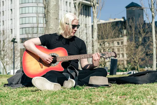 Jovem Albino Tocando Guitarra Relaxada Sentada Grama Apoiada Uma Árvore — Fotografia de Stock