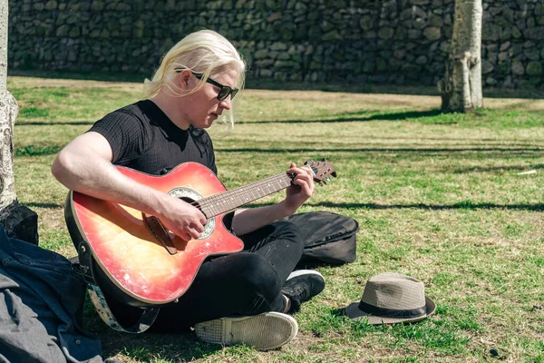 Jovem Albino Tocando Guitarra Relaxada Sentada Grama Apoiada Uma Árvore — Fotografia de Stock