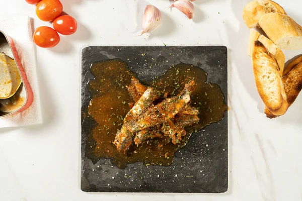 Aperatif olarak domates soslu sardalya dilimi ve tost ekmeğiyle birlikte otlar veriliyor. Üst görünüm.