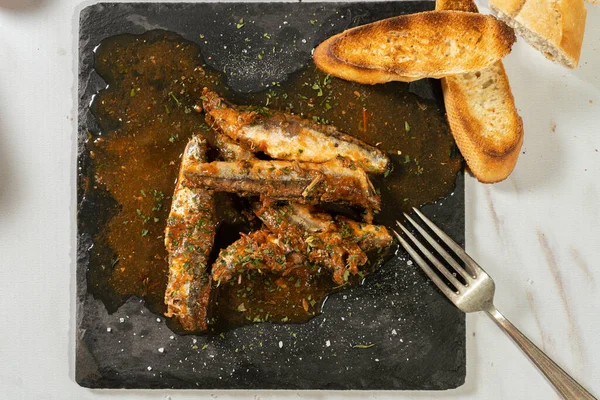 Aperatif olarak domates soslu sardalya dilimi ve tost ekmeğiyle birlikte otlar veriliyor. Üst görünüm.