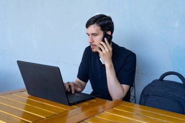 Uzaktan çalışan, dizüstü bilgisayarda yazan, cep telefonuyla konuşan, işleri yöneten bir adam. Bağımsız yaşam tarzı