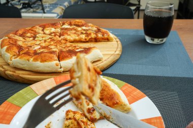 Tahtada dilimler halinde dilimlenmiş lezzetli pizzalar bir bardak sodayla birlikte yemeğe hazır.