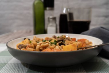 Maccheroni, patates, havuç, mantar ve soğanlı gulaş güveci kareli masa örtüsünde servis edilir.