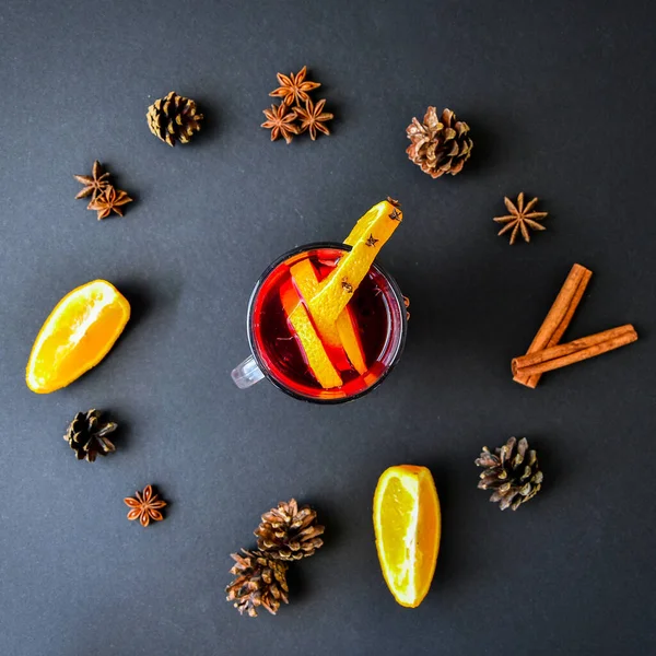 A clock in the form of spice for mulled wine on black background. Cinnamon sticks, anise stars, pine cones, slice of orange. Concept, creative work. Top view. Holiday atmosphere, Rustic style. The idea for creating greeting cards