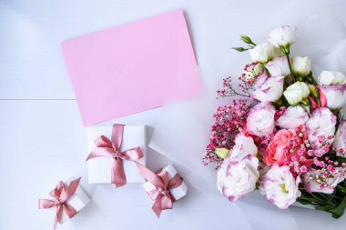 Zarif buket ve hediye kutularıyla kart maketi. Çiçek arkaplanı. Top view Flat Lay Holiday kartı 8 Mart, Sevgililer Günün kutlu olsun, Anneler Günü konsepti. Uzayı metin için kopyala. Tatil tebrik kartı.