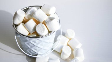 Beyaz mini marşmelov arka plan yakın çekim dokusu. Yemek arkaplanı. Uzayı kopyala Beyaz arkaplanda beyaz metal kova