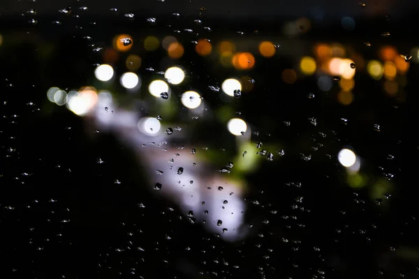 窗玻璃上的雨滴和夜灯的背景 模糊的灯光 摘要雨量背景 — 图库照片