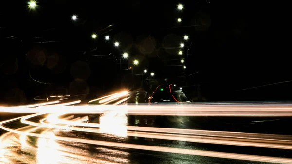 夜は車のライト 街路灯だ 夜の街 長時間露光写真ナイトロード 道路上の光の色のバンド 雨の後のぬれた道 — ストック写真