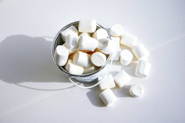 Beyaz mini marşmelov arka plan yakın çekim dokusu. Yemek arkaplanı. Uzayı kopyala Beyaz arkaplanda beyaz metal kova