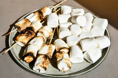 Çubukta kızaran lokum lokumları tabakta kızarıyor. Beyaz kamp şekerlemesi. Yaratıcı modern altyapı. Yaz Eğlencesi Kampı Sonbahar pikniği