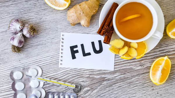 FLU - written on piece of paper among the products for the treatment of common cold - lemon, ginger, chamomile tea. Vitamin natural drink. Cinnamon anise star. Natural medicine vs conventional medicine