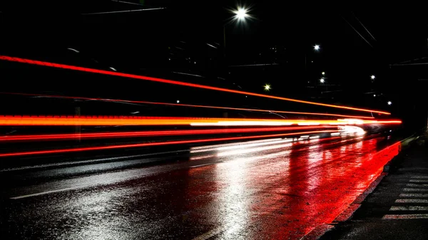 夜は車のライト 街路灯だ 夜の街 長時間露光写真ナイトロード 道路上の光の色のバンド 雨の後のぬれた道 — ストック写真