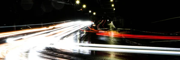 夜は車のライト 街路灯だ 夜の街 長時間露光写真ナイトロード 道路上の光の色のバンド 雨の後のぬれた道 — ストック写真