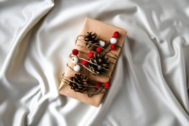 Şampanya renkli ipek arka planda süslemeleri olan sıfır ziyan Noel hediyesi. Uzayı kopyala Kartondan etiketli çevre dostu bir hediye. Yeni Yıl