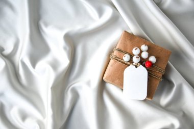 Şampanya renkli ipek arka planda süslemeleri olan sıfır ziyan Noel hediyesi. Uzayı kopyala Kartondan etiketli çevre dostu bir hediye. Yeni Yıl