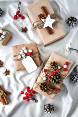 Şampanya renkli ipek arka planda süslemeleri olan sıfır ziyan Noel hediyesi. Uzayı kopyala Kartondan etiketli çevre dostu hediyeler. Yeni Yıl