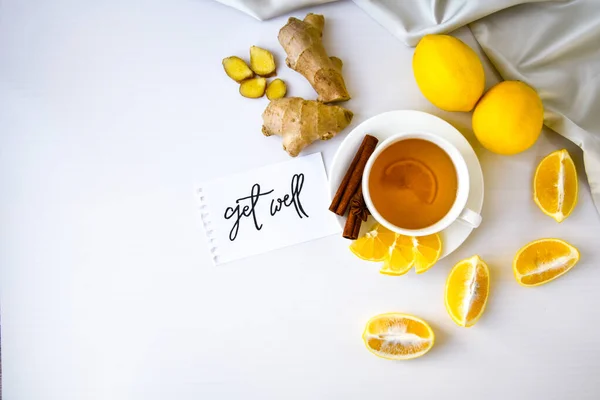 GET WELL - written on piece of paper among the products for the treatment of common cold - lemon, ginger, chamomile tea. Vitamin natural drink. Cinnamon anise star.