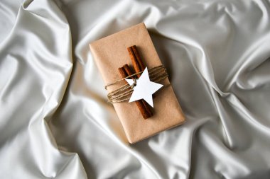 Şampanya renkli ipek arka planda süslemeleri olan sıfır ziyan Noel hediyesi. Uzayı kopyala Kartondan etiketli çevre dostu bir hediye. Yeni Yıl