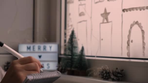 Zbliżenie kobiecej ręki piszącej list do Świętego Mikołaja. Ozdobiony na Boże Narodzenie, przygotowujący się do wakacji. Koncepcja świątecznego ducha, świąt i uroczystości 4K. — Wideo stockowe