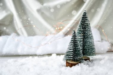 Şampanya renkli ipek arka planda iki Noel ağacı ve beyaz kar. Moda dekorasyonu. Noel bayramı kutlaması. Yeni yıl konsepti. Tebrik kartı. Noel arkaplanı köknar ağacı. Boşluğu kopyala