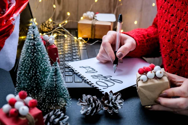 Noel süslerine karşı GIFT LIST yazılı kağıt, Noel Baba şapkalı dizüstü bilgisayar. Tatil çevrimiçi alışveriş. Kış indirimi. Noel ve Yeni Yıl 'a hazırlanın.