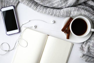 Not defteri kulaklıklı bir fincan kahve tarçın çubukları ve beyaz arka planda anason yıldızı. Etrafta süveter var. Kış sabahı rutini. Kahve molası. Uzayı kopyala Üst Manzara. Kahvaltıda. Düz yatıyordu