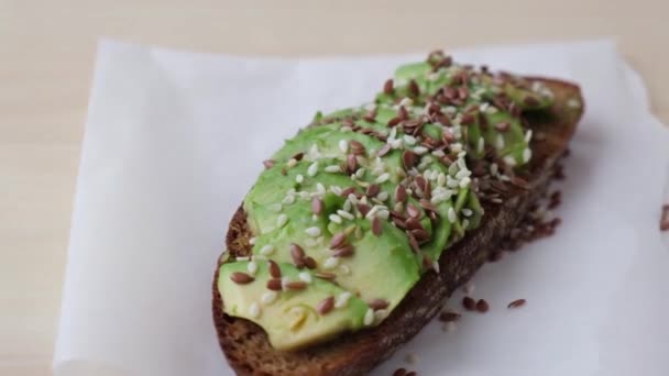 Zdravý avokádový toast rotující na dřevěné desce. Sezamová a lněná semena. Vegetariánské jídlo. — Stock video