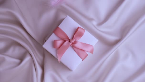 Penas de pássaro voando em caixa de presente branco com fita rosa. Conceito de férias fofo e delicado. — Vídeo de Stock