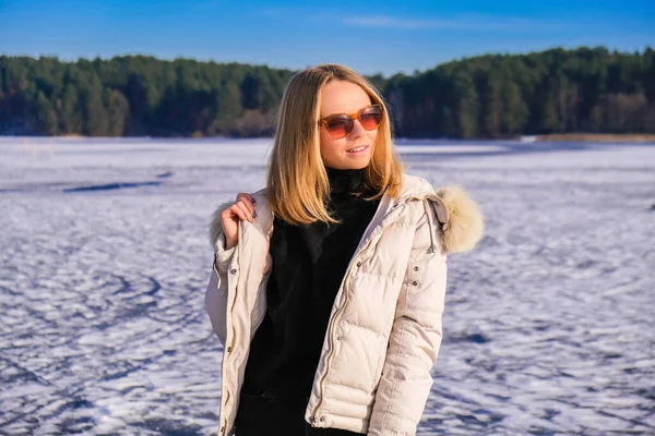 암컷은 웃으며 선글라스를 풍경을 바라본다 얼어붙은 호수에 머물고 있습니다 매력적 — 스톡 사진