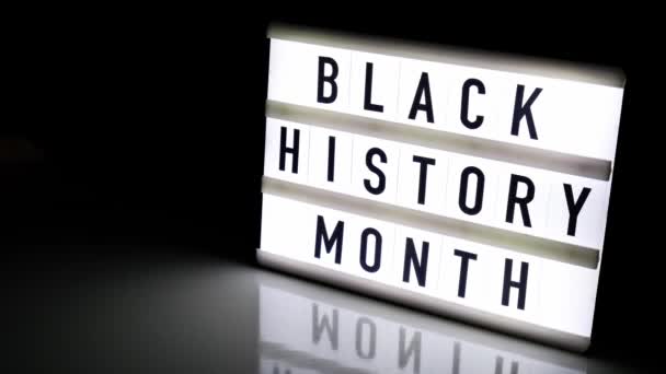 LightBox z tekstem BLACK HISTORY MONTH na ciemnym czarnym tle z odbiciem lustra. Wiadomość historyczna. 4k wideo. Powiększ — Wideo stockowe