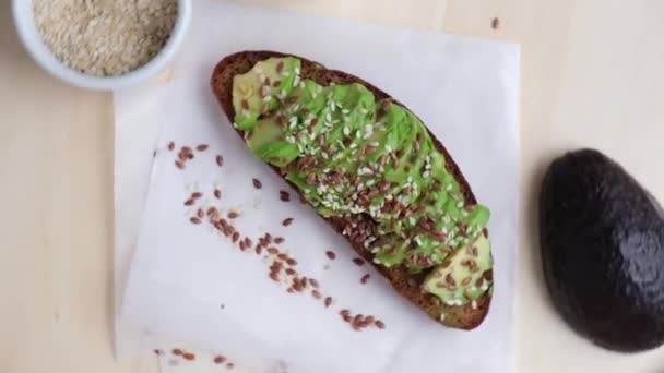 Friska avokado toast roterande på träskiva. Sesamfrön och linfrön. Vegetarisk mat. — Stockvideo