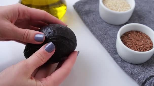 Le mani femminili tagliano l'avocado a metà. Avocado con puntini neri. Avocado fresco maturo, Colazione sana, Cibo vegetariano — Video Stock