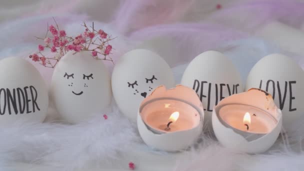 Filmación de encender una vela en huevos de Pascua Composición. Huevos de Pascua con caras sonrientes pintadas. Acogedora decoración interior del hogar, velas encendidas. Huevos de boda. Casado. — Vídeos de Stock