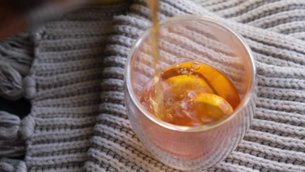 Průhledné sklo zdobené čerstvým citronem. Horký čaj nalévající se v šálku na pleteném svetru. Ranní snídaně. — Stock video