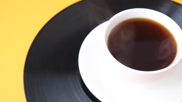 Een kop zwarte koffie staat op vinyl plaat. Dampende kop koffie. — Stockvideo