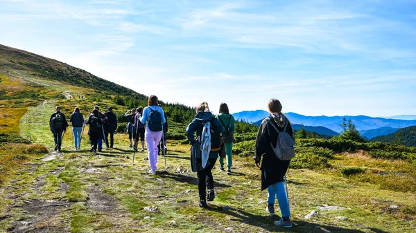 Back view of people hiking the mountains. Group of people hiking forward the pass. Group of hikers walking in the mountains