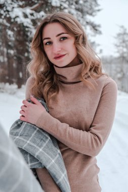 Kış ormanı geçmişindeki mutlu kadın. Ormandaki genç ve güzel kız. Neşeli güzel bir kadının portresi. Kış modası.