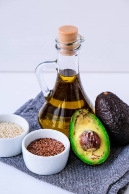 Cam şişede, susam ve keten tohumlu zeytin yağı. Taze olgun hass avokado. Sağlıklı beslenme. Vejetaryen malzemeleri. Vejetaryen diyeti. Beslenmek. Ketogenik diyet kavramı.