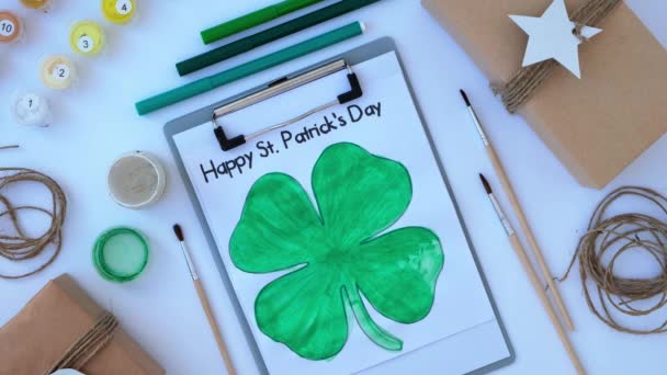 Female hands painting greeting card St Patricks day. Gift idea, decor craft. DIY. Do it yourself. Clovers, brush and paint. — Stock Video