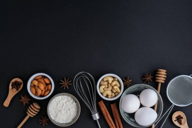 Siyah arka planda pişirme malzemeleri. Üst Manzara. Çerçeve kopyalama alanı. Ev yapımı: kurabiye, ekmek, pasta. Tarçın çubukları, ceviz, baharatlı yumurta unu.