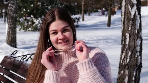 Piękna młoda kobieta w okularach na drutach w zimowym parku. Zimna pogoda na zewnątrz. Snow Happy uśmiechnięty portret dziewczyny — Wideo stockowe