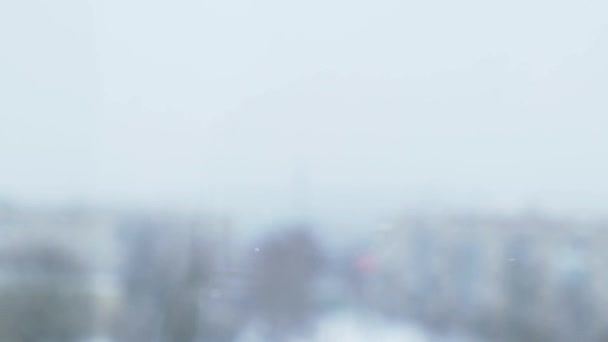 Cae la nieve en cámara lenta. Ciudad cubierta de nieve y copos de nieve voladores en cámara lenta. Desenfocado. Enfoque selectivo. Fondo de invierno borroso clima frío — Vídeos de Stock