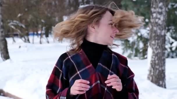 Lockigt blond söt ung kvinna i poncho i vinterparken. Kallt väder. Semester, säsong och fritid koncept. Jul, nyår. — Stockvideo