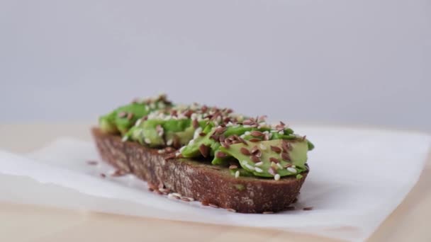 Zdravý avokádový toast rotující na dřevěné desce. Sezamová a lněná semena. Vegetariánské jídlo. — Stock video