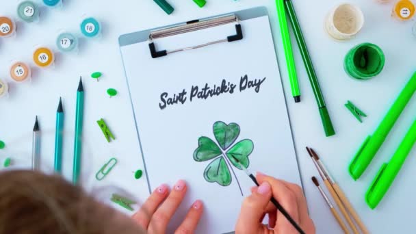 Female hands painting greeting card St Patricks day. Gift idea, decor craft. DIY. Do it yourself. Clovers, brush and paint. — Stock Video