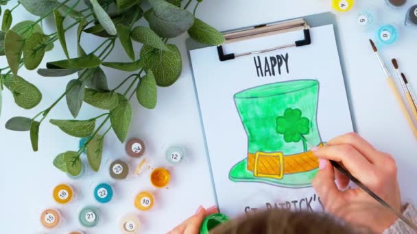 Female hands painting greeting card St Patricks day. Gift idea, decor craft. DIY. Do it yourself. Clovers, brush and paint. — Stock Video