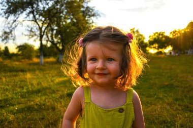 Küçük bir kızın portresi. Küçük sevimli çocuk ilgi ve gülümseme ile bakıyor. Yaz güneşi