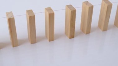 Domino etkisi, tahta domino taşlarının beyaz arka plana düşmesi. Dominolar peş peşe düşüyor, eller Domino 'yu itiyor ve zincirleme reaksiyon oyunu başlatıyor..