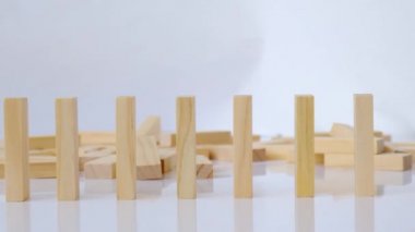 Domino etkisi, tahta domino taşlarının beyaz arka plana düşmesi. Dominolar peş peşe düşüyor, eller Domino 'yu itiyor ve zincirleme reaksiyon oyunu başlatıyor..